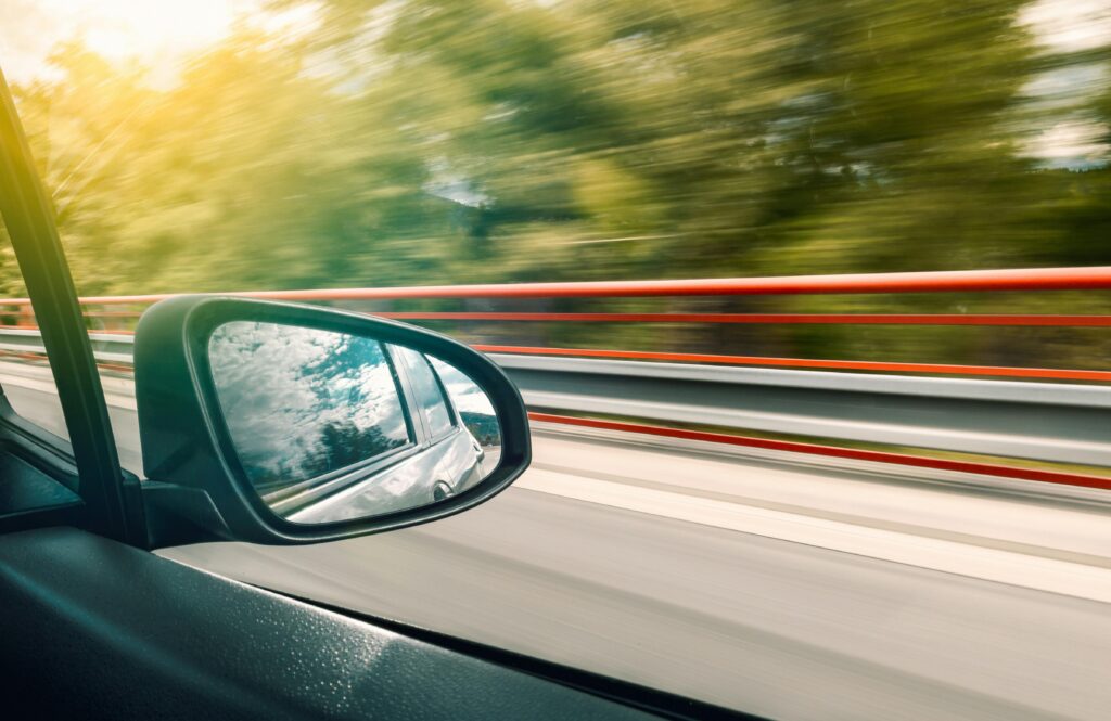 Picture of a car mirror while it is driving down the road