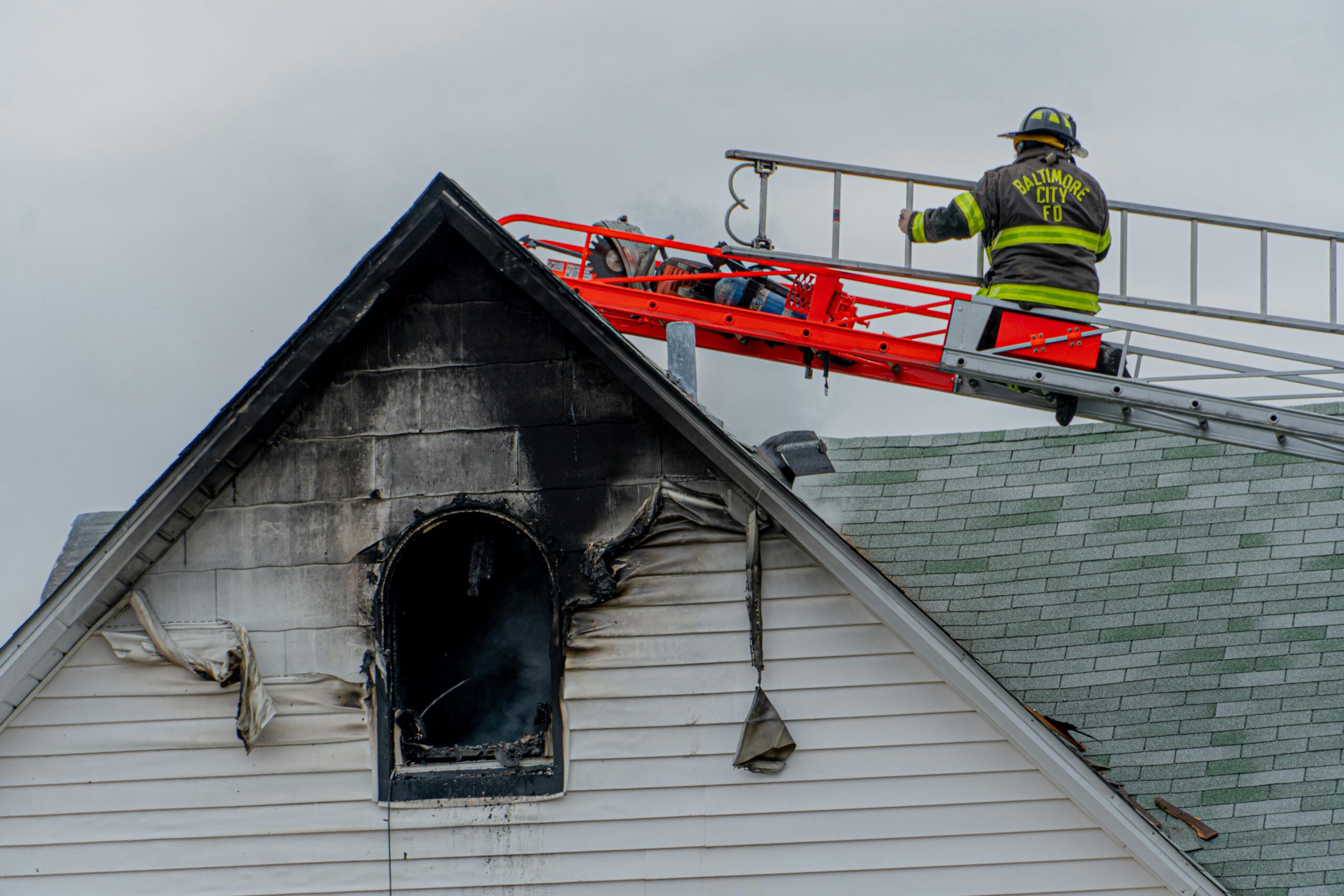 Firefighter on a ladder above a house fire